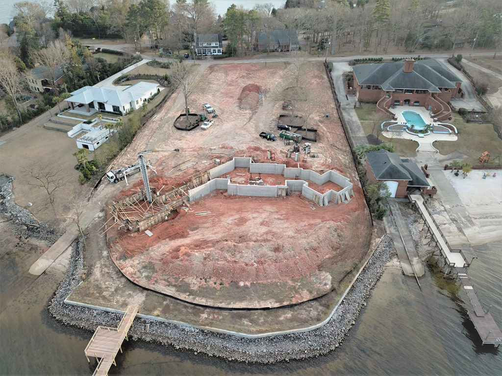 A waterfront property with partially built walls and cleared land.