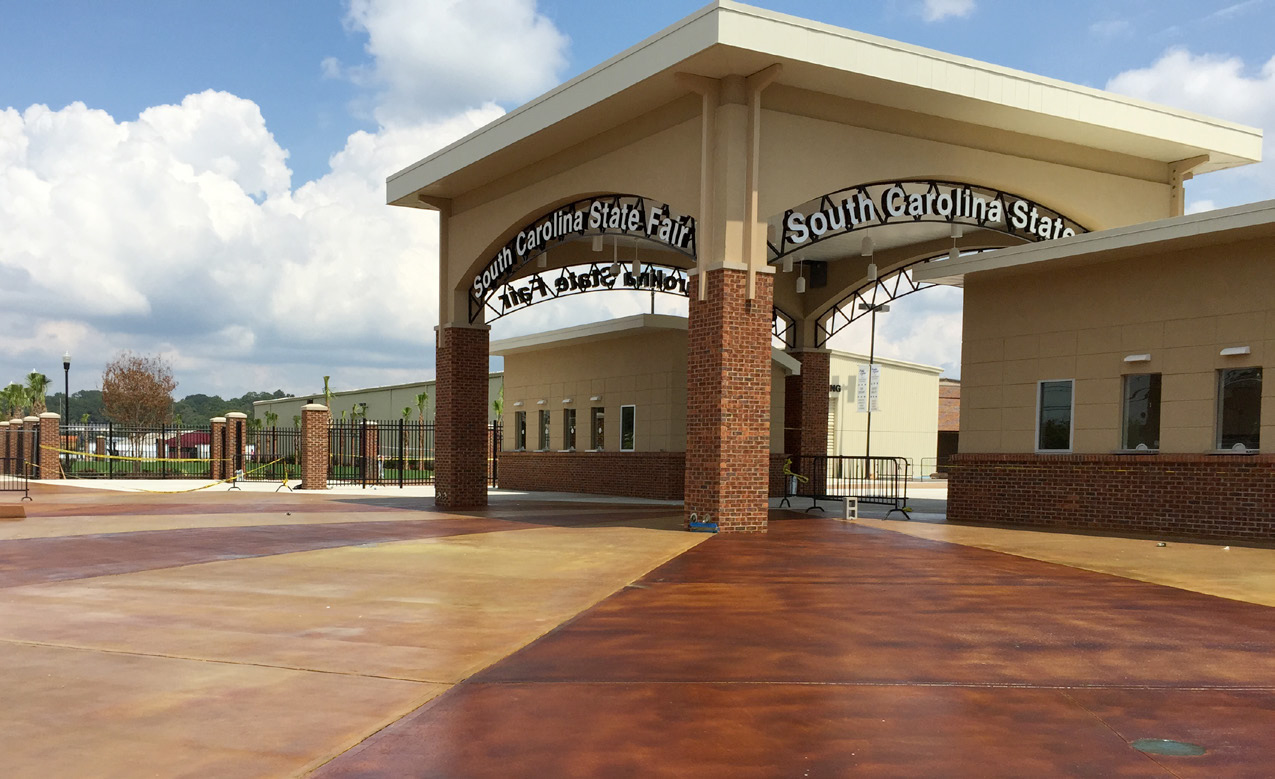 Entrance archway of a sports complex under a partly cloudy sky.